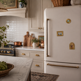 Vintage-style kitchen with a white refrigerator, marble countertops, and decorative elements.
