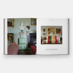 Open book showing interior design images of a room with striped chair and colorful sofa.