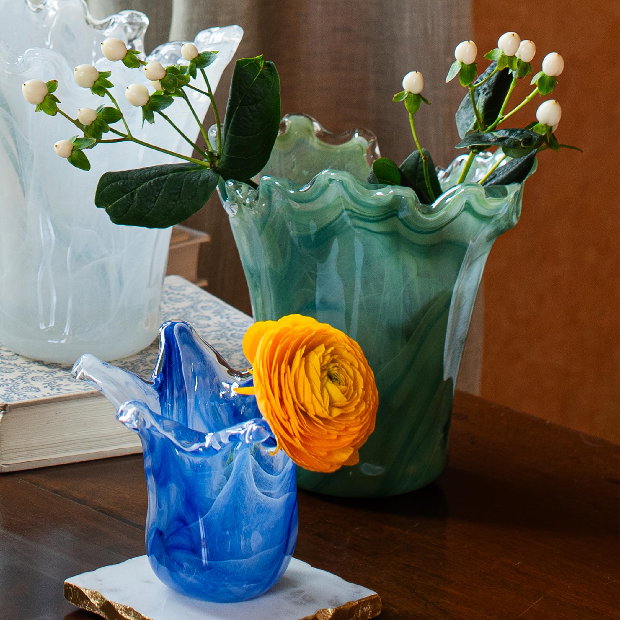 Decorative onda glass vases with flowers on a wooden surface
