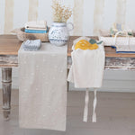 Decorative table setting with a star-patterned runner and a lemon-themed towel on a wooden table.