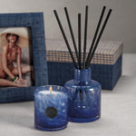 Blue candle and diffuser set with a blurred photo in the background
