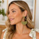 Woman wearing green earrings and a floral dress, smiling.