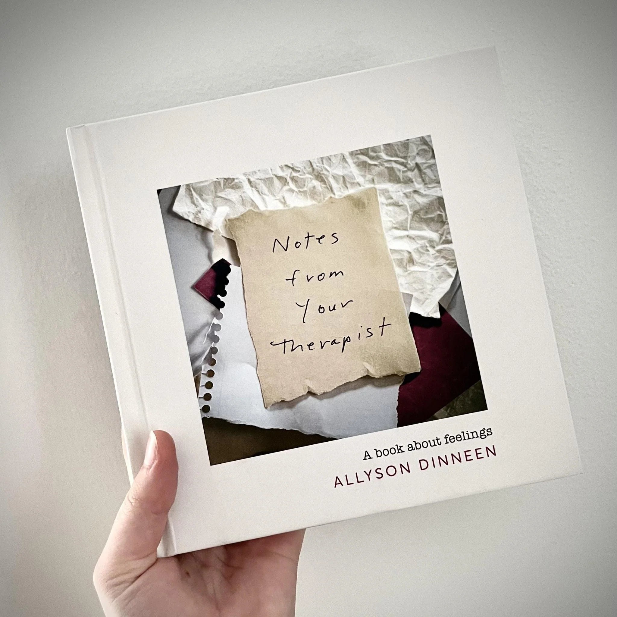 Book titled 'Notes from Your Therapist' by Allyson Dinneen held by a hand on a light gray background