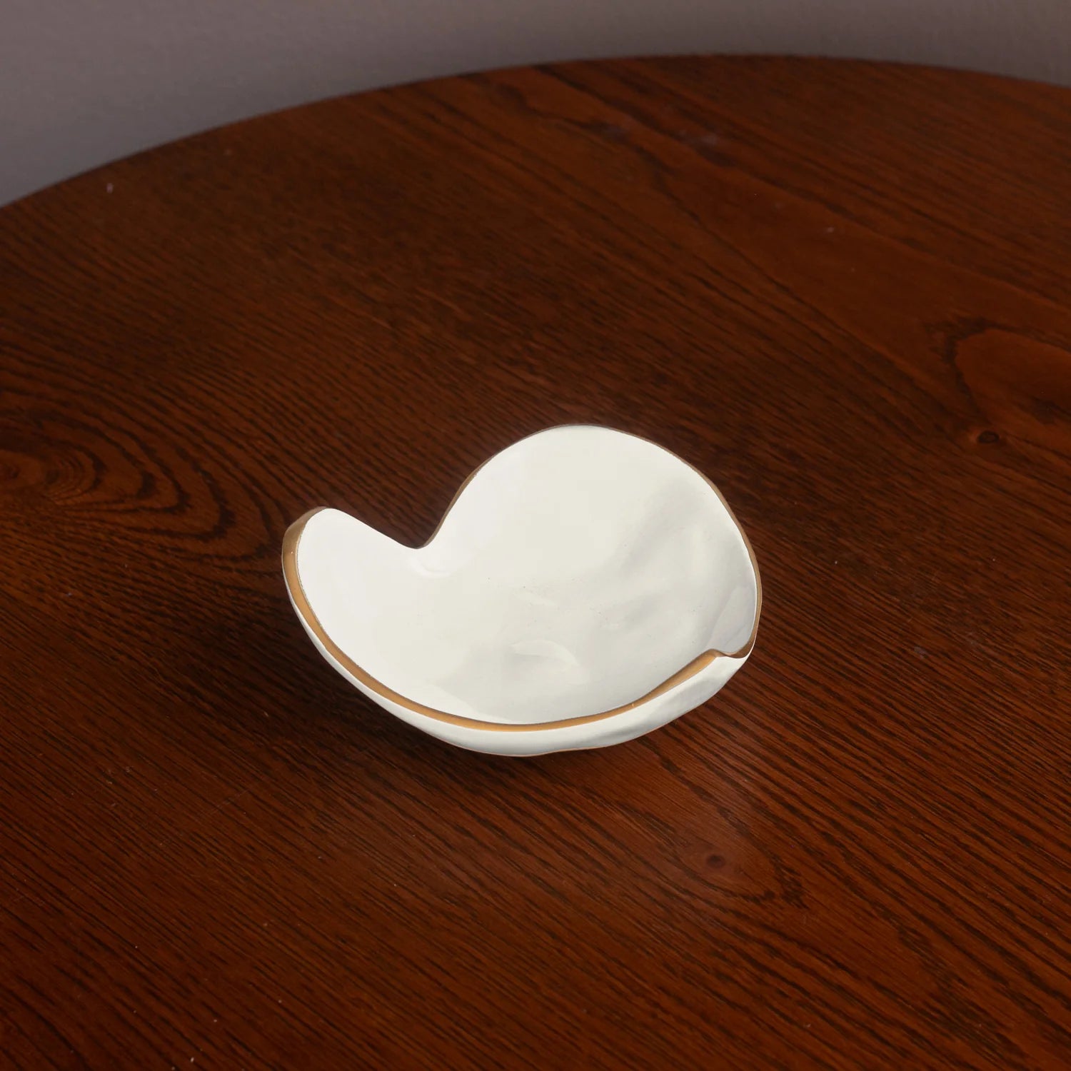 White ceramic shell-shaped dish on a wooden surface