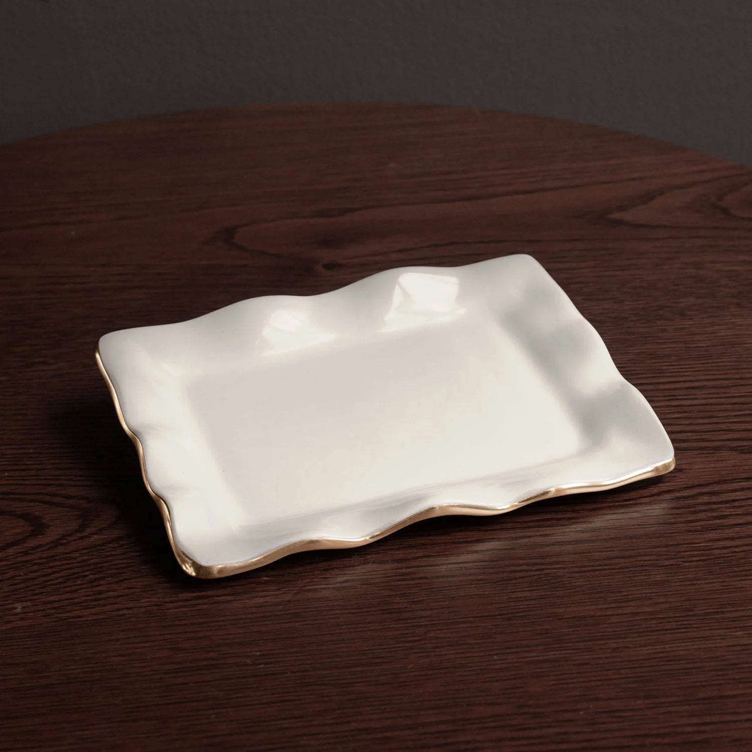 Rectangular white ceramic plate with gold rim on a dark wooden surface