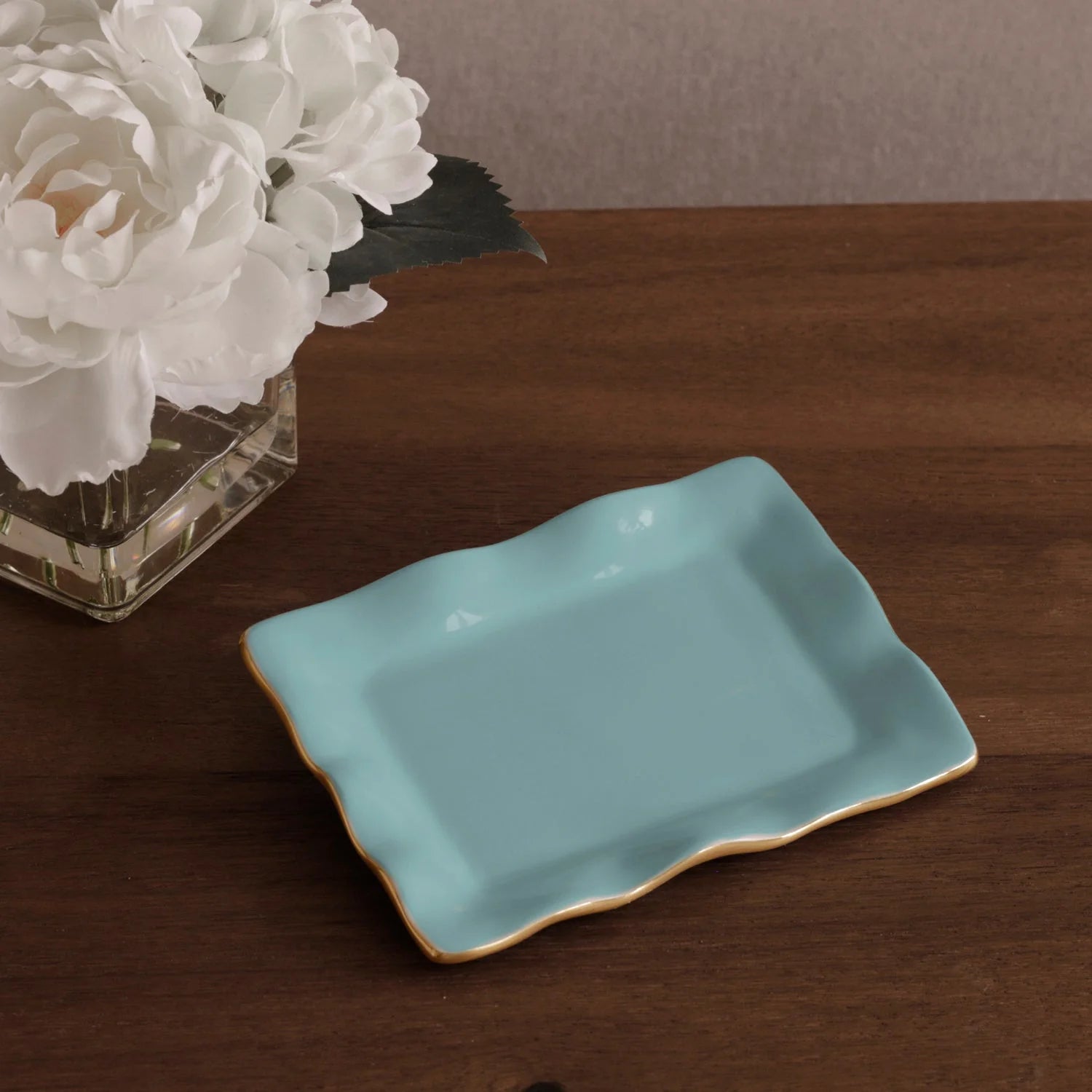 encanto vento small rectangular tray turquoise on white background on a wooden surface with white flowers in the background