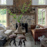 Cozy living room with stone fireplace, brown leather sofa, and wooden walls.