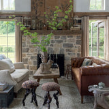 Cozy living room with stone fireplace, brown leather sofa, and wooden walls.