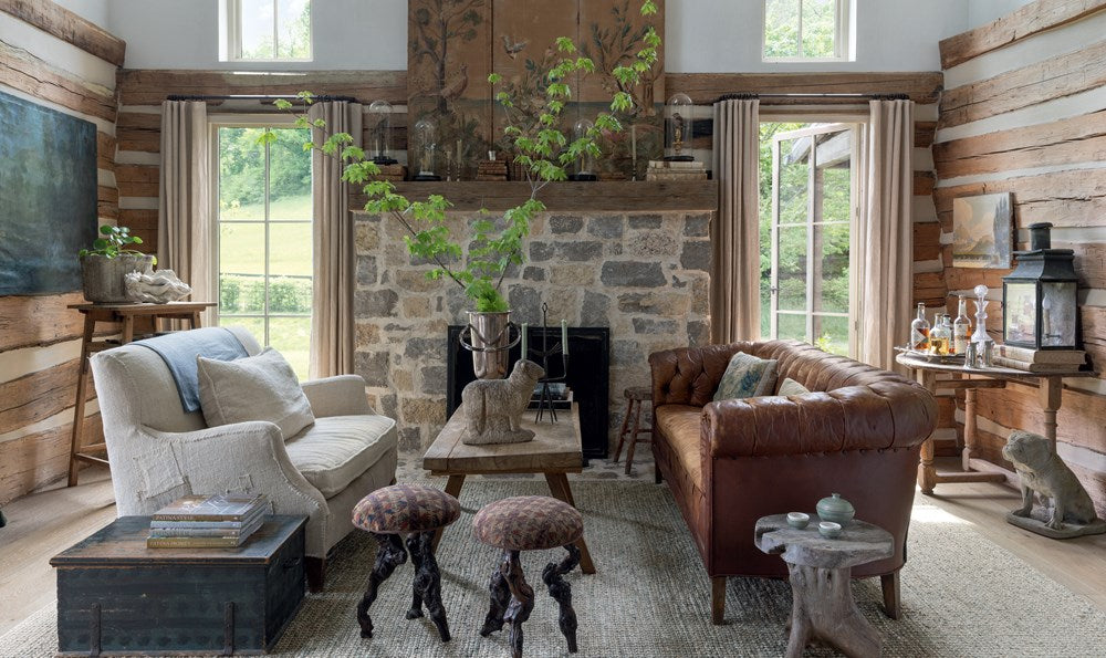 Cozy living room with stone fireplace, brown leather sofa, and wooden walls.