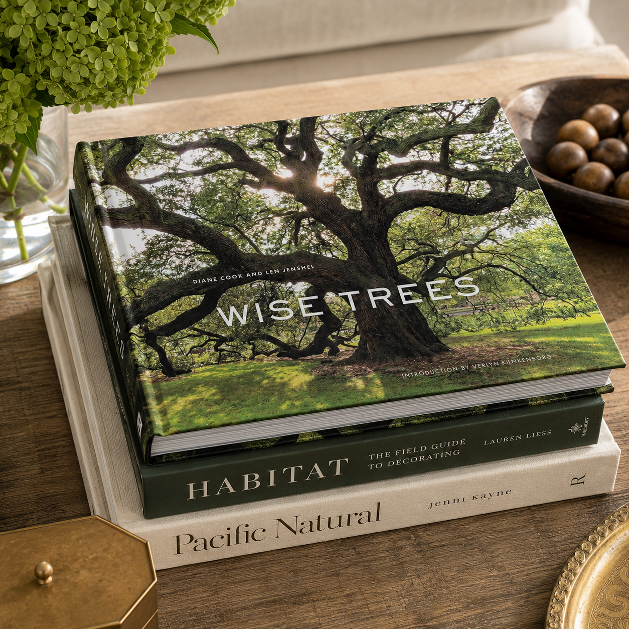 Stack of books titled 'Wise Trees', 'Habitat', and 'Pacific Natural' on a wooden surface.