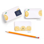 Notebook with lemon design, pencil, and branded packaging on a white background