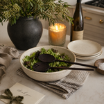 Dining table setting with a bowl of salad, wine, and candle