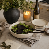 Dining table setting with a bowl of salad, wine, and candle