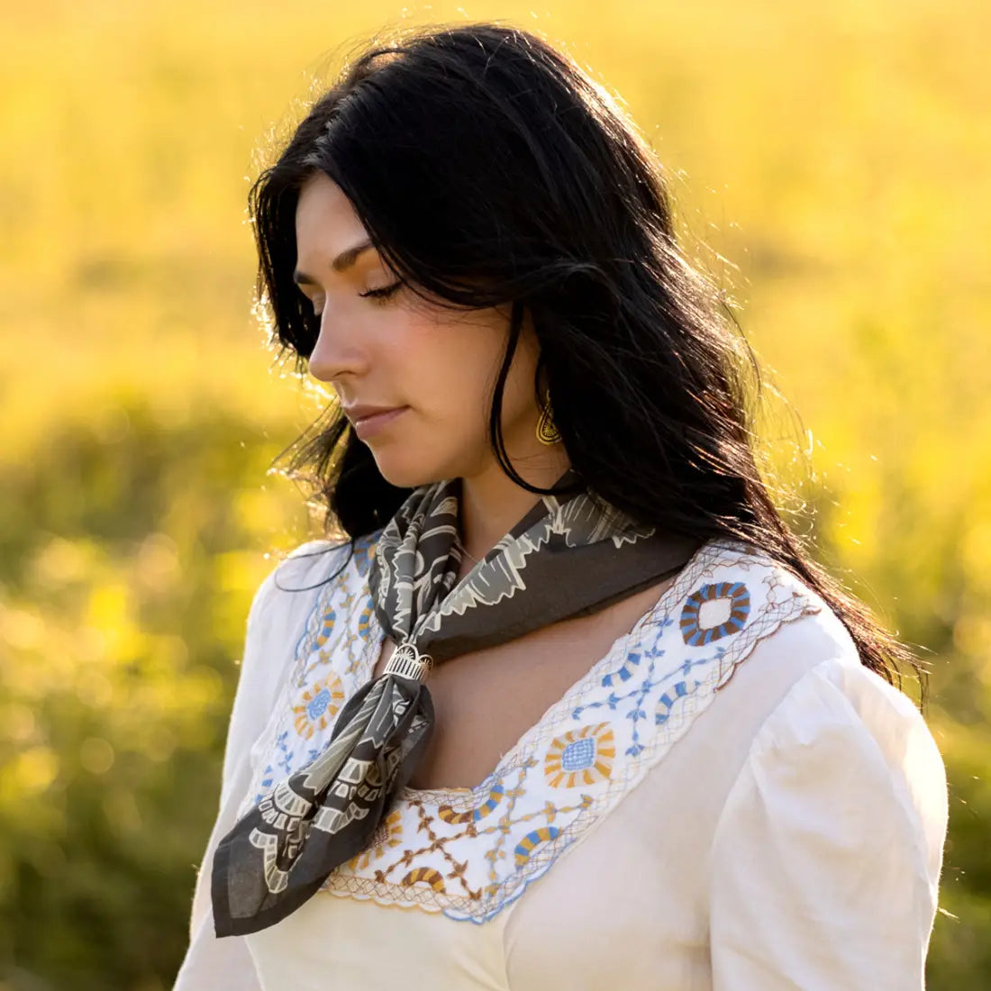 Woman wearing a patterned scarf in a field with blurred yellow background