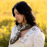 Woman wearing a patterned scarf in a field with blurred yellow background