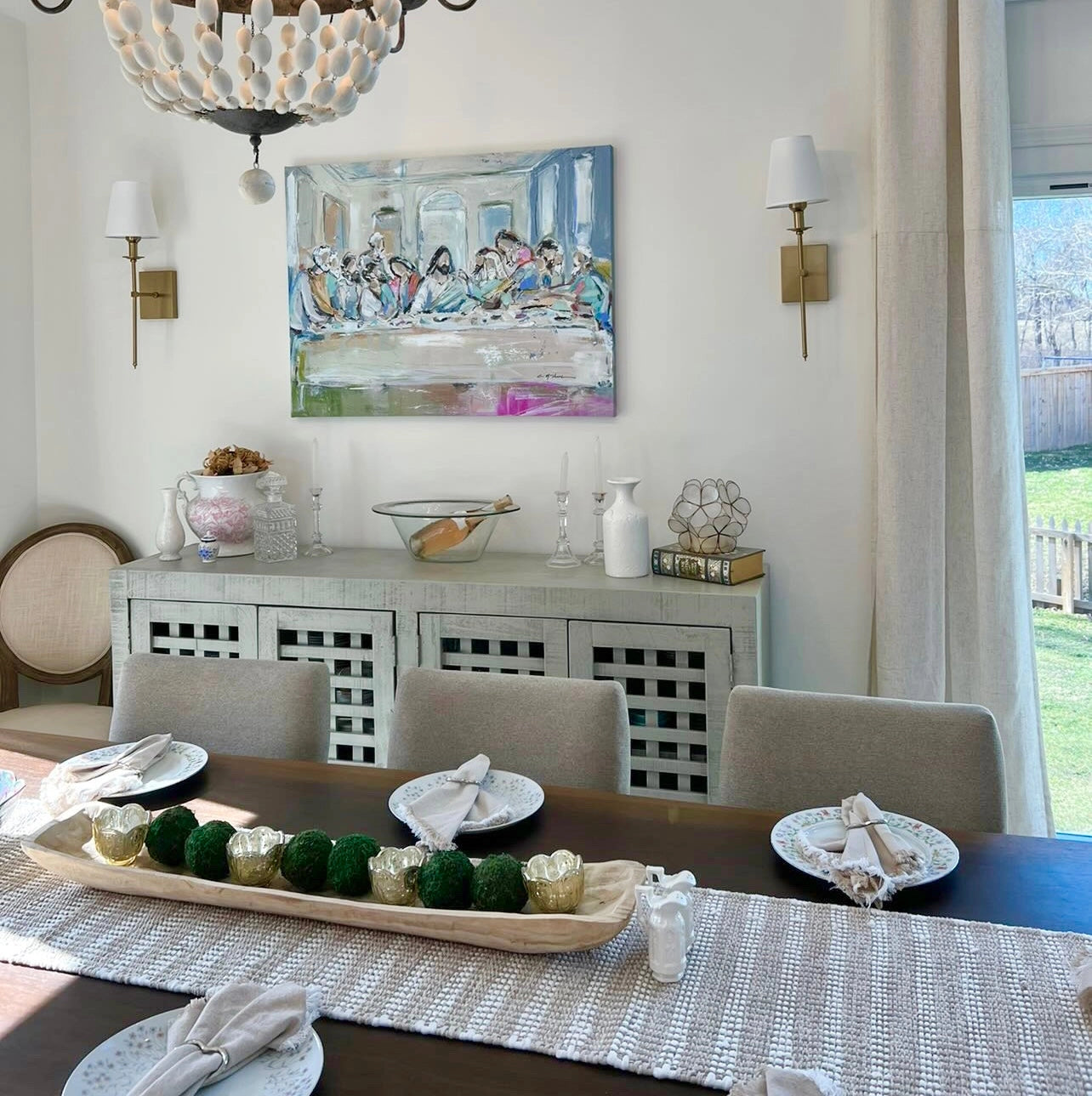 Dining room with a table set for four, decorative items, and a painting on the wall.