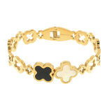 Gold bracelet with black and white clover-shaped charms on a white background