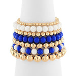 Set of beaded bracelets in gold, blue, and white on a white background