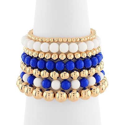 Set of beaded bracelets in gold, blue, and white on a white background