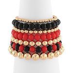 Stack of beaded bracelets in gold, black, and red on a white background