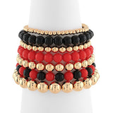 Stack of beaded bracelets in gold, black, and red on a white background