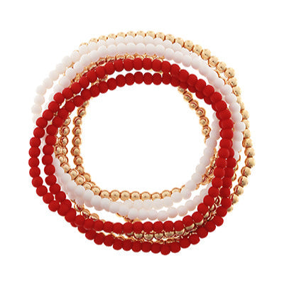 Set of red, white, and gold beaded bracelets on a white background