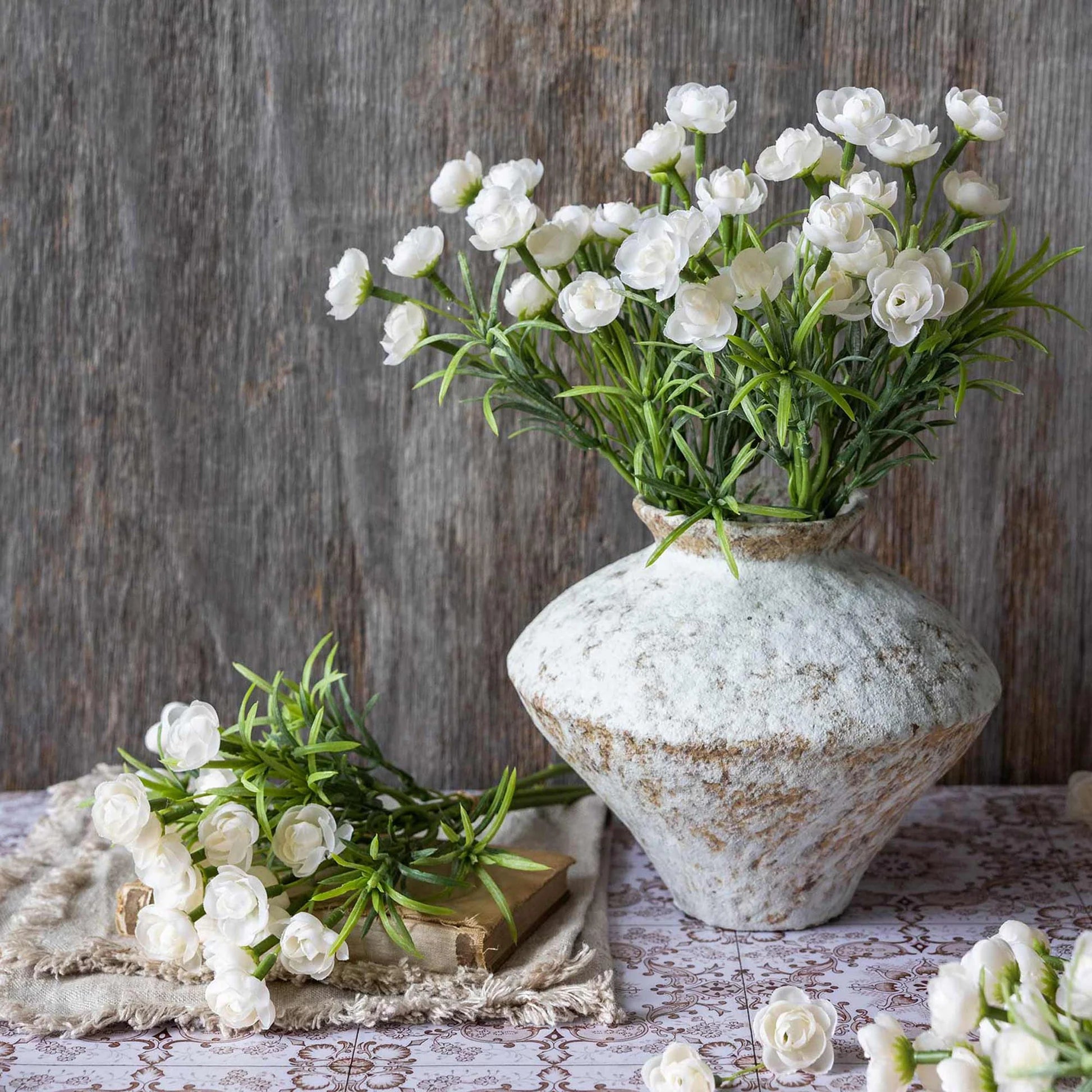 White flowers in a textured vase on a wooden surface