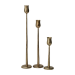 three antique gold candesticks in varying heights on a white background