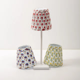 Set of three floral-patterned lampshades on a white stand against a white background