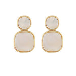 gold-framed earrings featuring two stacked pearlescent stones, one round and one square, displayed on a white background