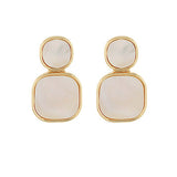 gold-framed earrings featuring two stacked pearlescent stones, one round and one square, displayed on a white background