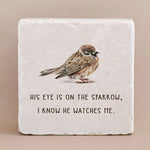 Decorative stone with engraved text "His eye is on the sparrow, i know he watches me" and an image of a bird on a beige background