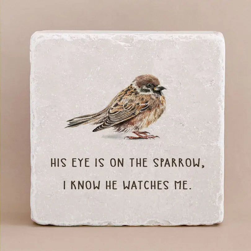 Decorative stone with engraved text "His eye is on the sparrow, i know he watches me" and an image of a bird on a beige background