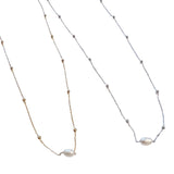 Two delicate necklaces, one in gold and one in silver, each featuring a single freshwater pearl pendant and beaded accents on the chain, displayed on a white backgroun