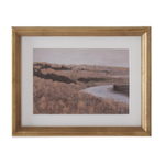 Framed landscape print of a river and trees with a gold frame on a white background