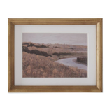 Framed landscape print of a river and trees with a gold frame on a white background