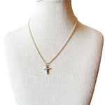 Liana Necklace features a gold beaded chain and a cross charm accented with subtle blue details. 