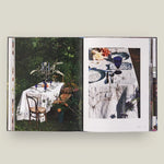 Open book showing images of a table setting outdoors with chairs.