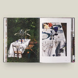 Open book showing images of a table setting outdoors with chairs.