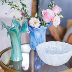 Decorative glass vases and bowl on a table with flowers.