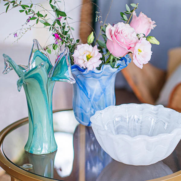 Decorative glass vases and bowl on a table with flowers.