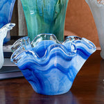 Blue glass vase with wavy design on a wooden surface