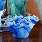 Blue glass vase with wavy design on a wooden surface