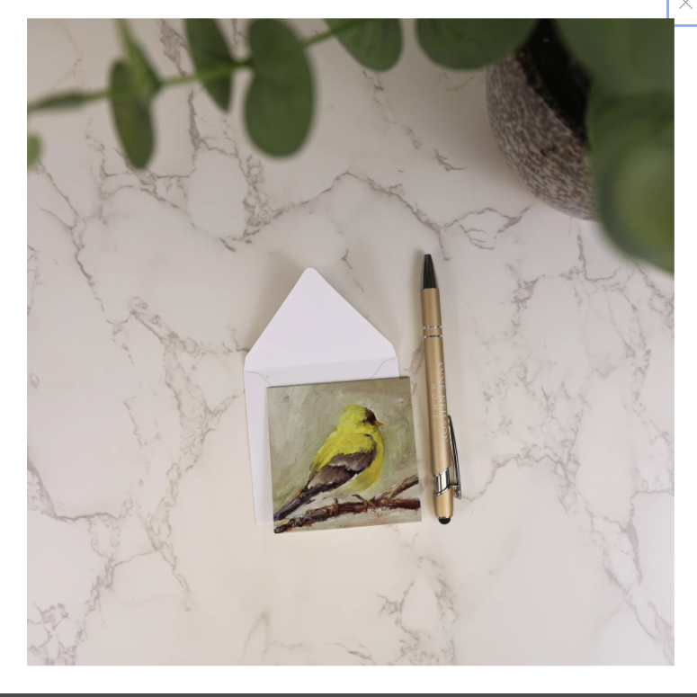 Notebook with bird illustration, pen, and house-shaped object on a marble surface