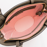 Open handbag with red and white striped lining on a white background
