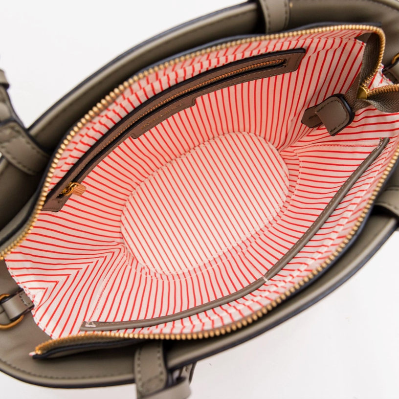 Open handbag with red and white striped lining on a white background