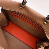 Close-up of a beige handbag with a red interior