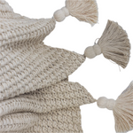 Beige knitted throw blanket with tassels on a white background