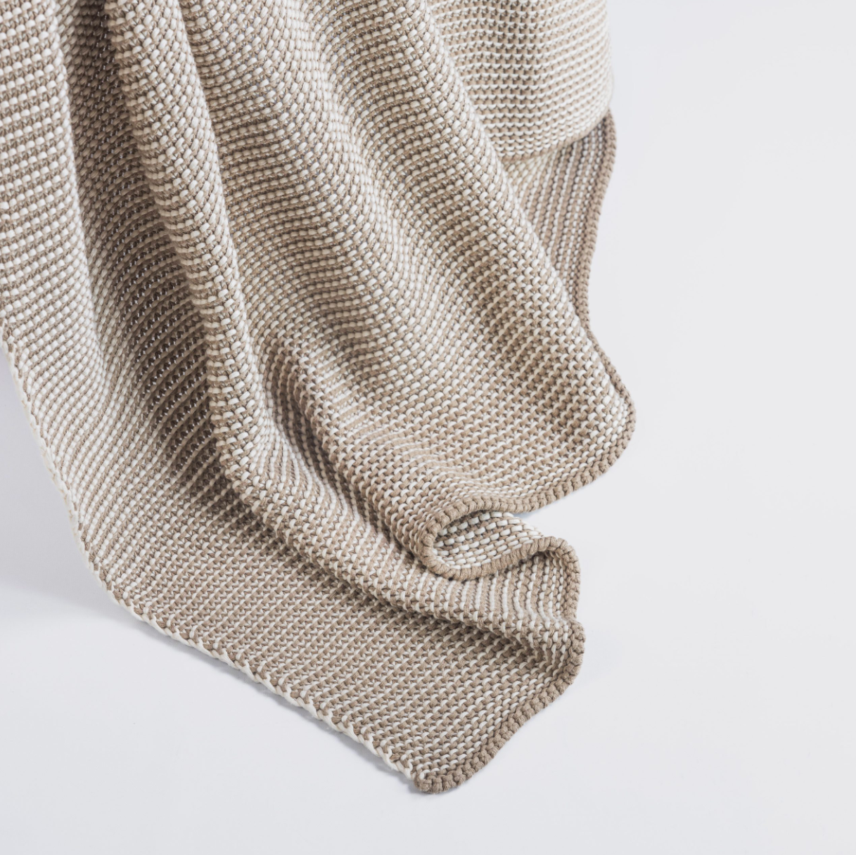 Knitted beige blanket on a light gray background