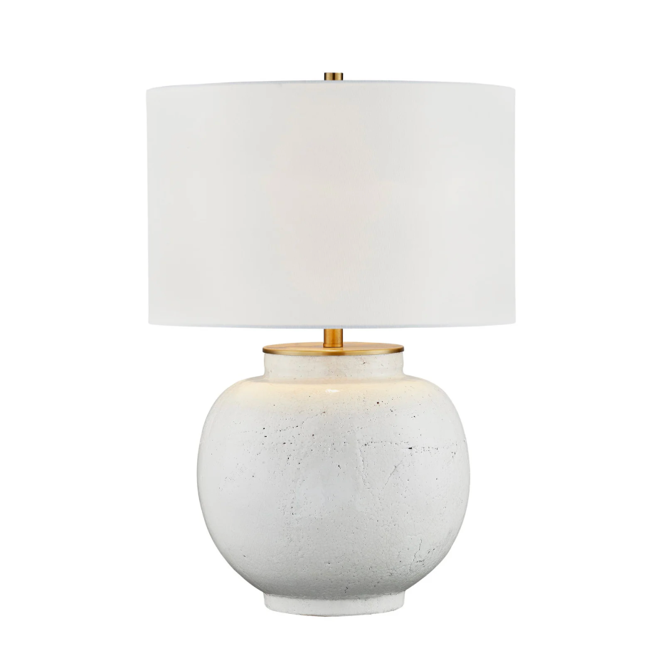 Table lamp with a white textured base and gold accents on a white background